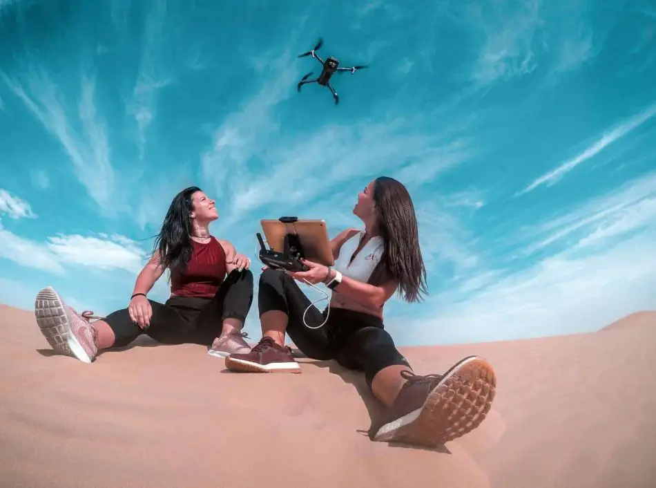 girls on beach watching drone