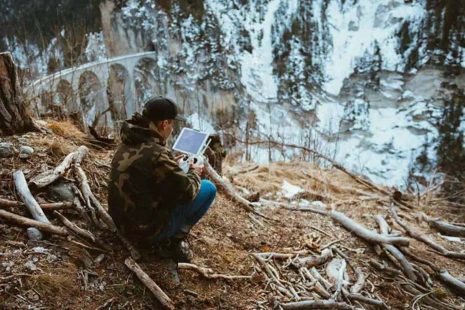 man in woods controlling drone