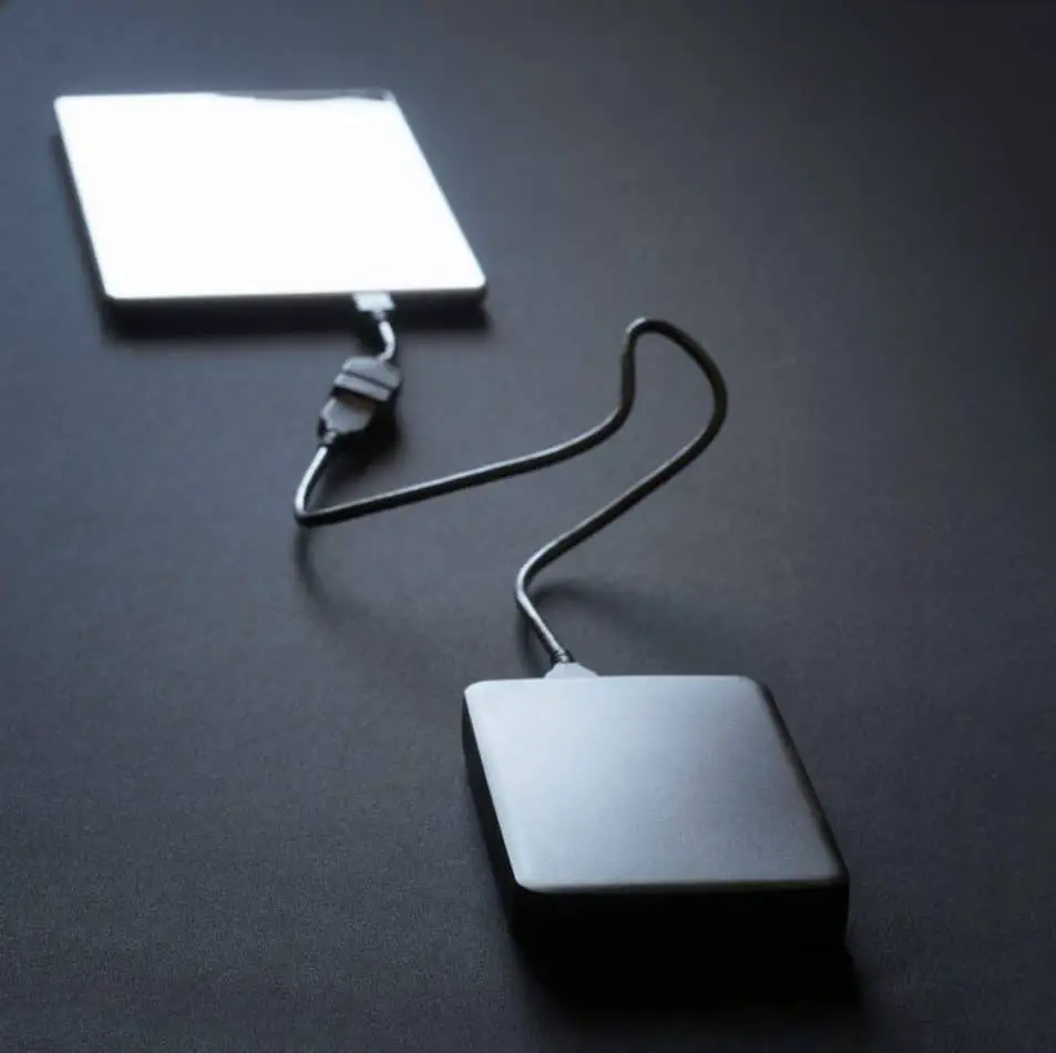 Black external hard drive connected with a wire to a tablet