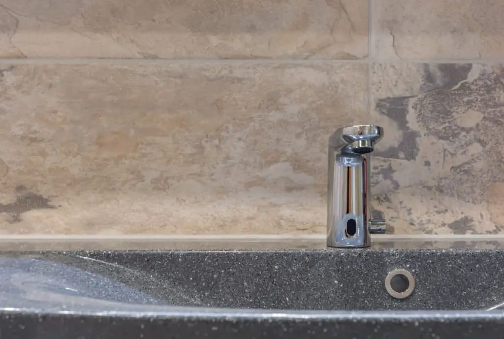 Sink in a bathroom with modern bathroom tap and tiles in natural stone look