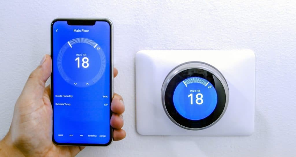 smart phone using a wireless Thermostat on a white wall