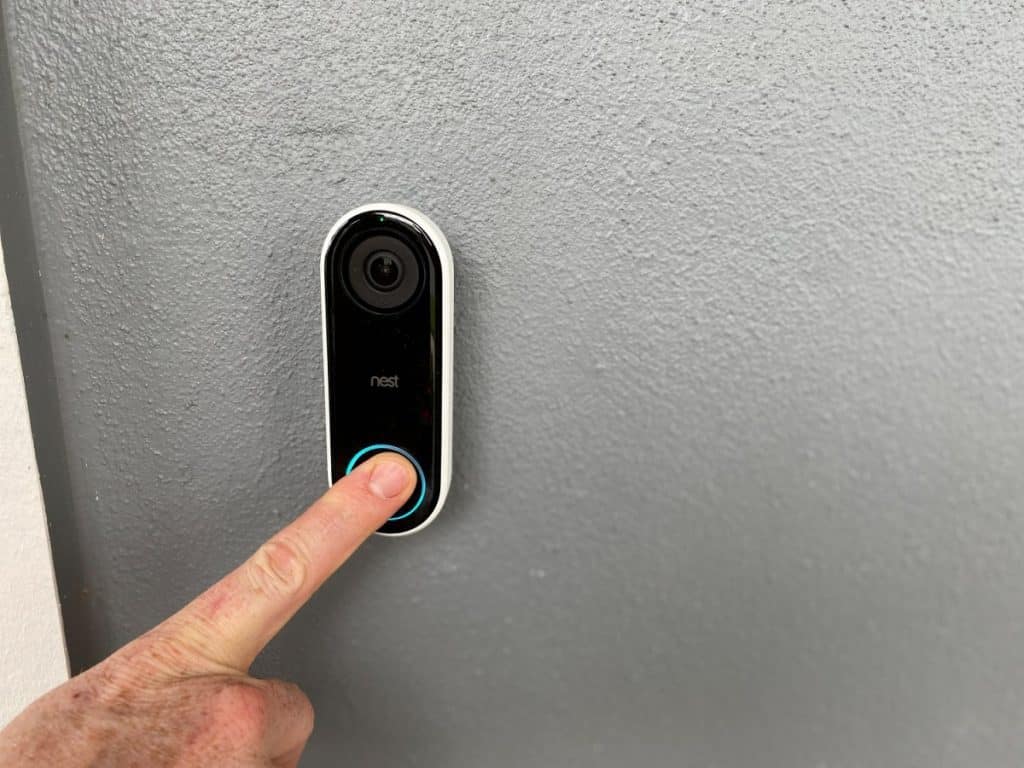 A person pressing a Ring doorbell