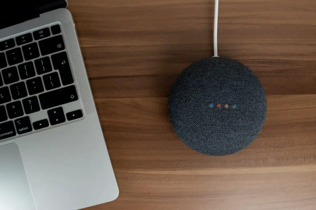 Google Home Mini charcoal smart speaker on a wooden desk