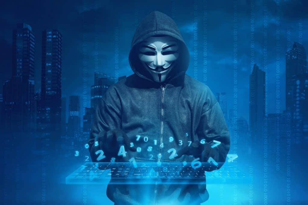 Hooded man with anonymous mask hacking system online security