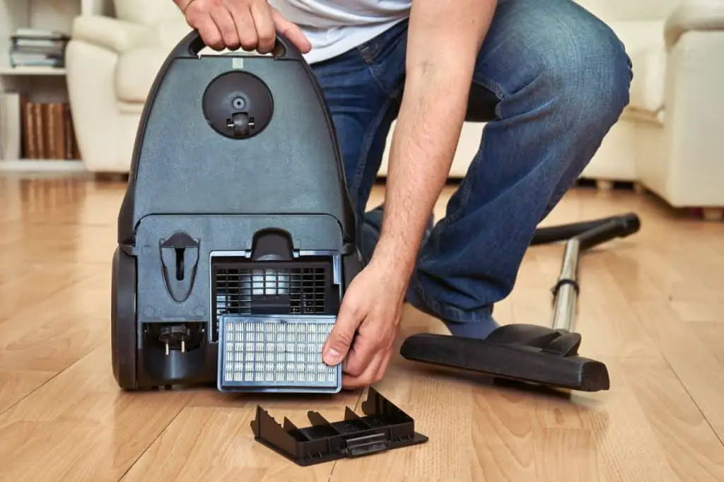 Man replacing an air filter in vacuum cleaner at home