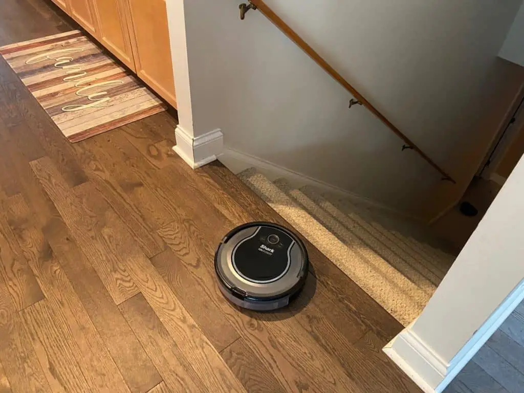 robot vacuum on hardwood by stairs